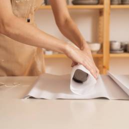 anonymous artisan wrapping ceramic cups in the paper